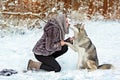 Cute girl in grey coat kisses husky dog on the background of the Royalty Free Stock Photo