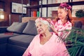 Cute girl with hair rollers brushing hair of her lovely grandmother