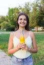 Cute girl is having a walk in the park holding a bottle of orange juice in a sunny wam day Royalty Free Stock Photo