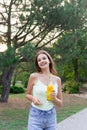 Cute girl is having a walk in the park holding a bottle of orange juice in a sunny wam day Royalty Free Stock Photo