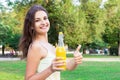 Cute girl is having a walk in the park holding a bottle of orange juice in a sunny wam day Royalty Free Stock Photo