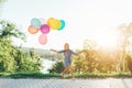 Cute girl holding colorful balloons in the city park, playing an Royalty Free Stock Photo