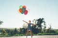 Cute girl holding colorful balloons in the city park dreaming Royalty Free Stock Photo