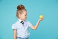 Cute girl holding green apple isolated on the blue background. Royalty Free Stock Photo