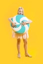 A cute girl is holding a huge blue and white candy on a yellow background. Sweet gift. Large lollipop. Christmas sweetness. Royalty Free Stock Photo