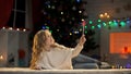 Cute girl holding magic wand, making wishes near Christmas tree, fairy-tale Royalty Free Stock Photo