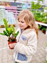 Cute girl holding potted plant in a flower shop. Little farmer choosing and buying green plants for home. Happy child. Royalty Free Stock Photo