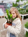 Cute girl holding potted plant in a flower shop. Little farmer choosing and buying green plants for home. Happy child. Royalty Free Stock Photo