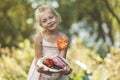 Cute girl holding vegetables from the garden, fresh rural products in a hat