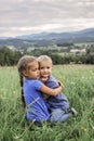 Cute 7-8 years girl hugging her smaller on the top of the mountains in summer