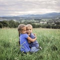 Cute 7-8 years girl hugging her smaller on the top of the mountains in summer