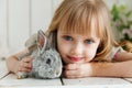 Cute girl hugging with rabbit while lying on the floor at home Royalty Free Stock Photo