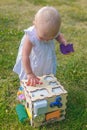 Cute girl inserts figures into the recesses on the development board. Toys for the development of fine motor skills and logic for Royalty Free Stock Photo