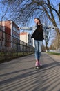 cute girl in jeans and pink sneakers rides a penny skate longboard around the city. International Skateboarding Day. Sports Royalty Free Stock Photo