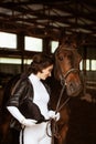 Cute girl jockey, next to beautiful brown horse shooting close-up. beautiful Royalty Free Stock Photo