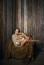 Cute girl in knee socks and sweater with Teddy bear in her hands sitting in armchair in wooden room Royalty Free Stock Photo