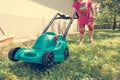 Cute girl lawn mowing with plastic toy mower. Royalty Free Stock Photo