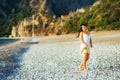 A cute girl in a light summer sundress and a straw hat in her hands is walking along a deserted paradise beach. Royalty Free Stock Photo