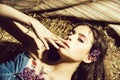 Cute girl with lilac flowers lying on hay