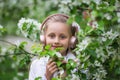 Cute girl listening to music in an apple blossom tree. adorable blonde enjoying music in headphones outdoors in a park. Children`