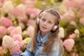 Cute girl listening to music in an blossom. adorable blonde enjoying music in headphones outdoors in a park. headphone portrait