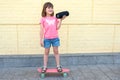 A cute girl listens to music and rides a skateboard against on a background a brick yellow walls. Sports.  Lifestyle Royalty Free Stock Photo