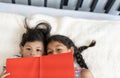 Cute girl and little boy reading a book while lying on bed at home Royalty Free Stock Photo