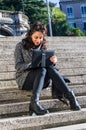 Cute girl looking at her tablet and sitting on stairs