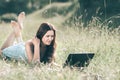 Cute girl looking at the screen of her laptop while lying on the grass Royalty Free Stock Photo