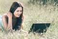 Cute girl looking at the screen of her laptop while lying on the grass Royalty Free Stock Photo