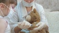 Cute girl makes an injection to toy bear. baby plays in a medical mask. child plays in hospital. game pretends to be Royalty Free Stock Photo