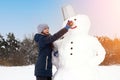 Cute girl makes snowman on winter day. Girl on a snow-covered field in the open air. Artistically colored photography