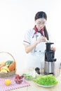 A cute girl makes vegetable juice, with carrot apple orange cranberry beetroot and mango in chef suit Royalty Free Stock Photo