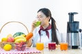 A cute girl makes vegetable juice, with carrot apple orange cranberry beetroot and mango in chef suit Royalty Free Stock Photo