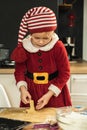 Cute girl making dough for Christmas cookies. Little kid wearing Christmas outfit and having fun while cooking in the kitchen. Royalty Free Stock Photo