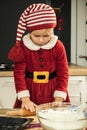 Cute girl making dough for Christmas cookies. Little kid wearing Christmas outfit and having fun while cooking in the kitchen. Royalty Free Stock Photo