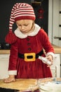 Cute girl making dough for Christmas cookies. Little kid wearing Christmas outfit and having fun while cooking in the kitchen. Royalty Free Stock Photo