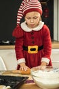 Cute girl making dough for Christmas cookies. Little kid wearing Christmas outfit and having fun while cooking in the kitchen. Royalty Free Stock Photo