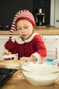 Cute girl making dough for Christmas cookies. Little kid wearing Christmas outfit and having fun while cooking in the kitchen. Royalty Free Stock Photo