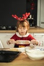 Cute girl making dough for Christmas cookies. Little kid wearing Christmas outfit and having fun while cooking in the kitchen. Royalty Free Stock Photo