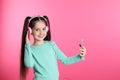 Cute girl with mobile phone enjoying music in headphones on color background Royalty Free Stock Photo