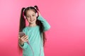 Cute girl with mobile phone enjoying music in headphones on color background Royalty Free Stock Photo