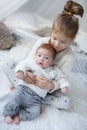 Cute girl with a newborn baby brother relaxing together on a white bed Royalty Free Stock Photo