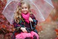 Cute girl with an old suitcase and an umbrella in her hand on a footpath in the autumn forest Royalty Free Stock Photo