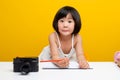 girl pictures Asia writes a book In the office for hardworking kids. Smart kids. White table on a yellow background
