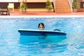 Cute girl playing with a bodyboard in a swimming pool. Royalty Free Stock Photo