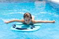 Cute girl playing with a bodyboard in a swimming pool. Royalty Free Stock Photo