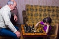 Cute girl playing chess at home with her grandfather Royalty Free Stock Photo