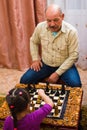 Cute girl playing chess at home with her grandfather Royalty Free Stock Photo