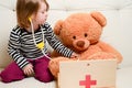 Cute girl playing doctor with plush toy bear